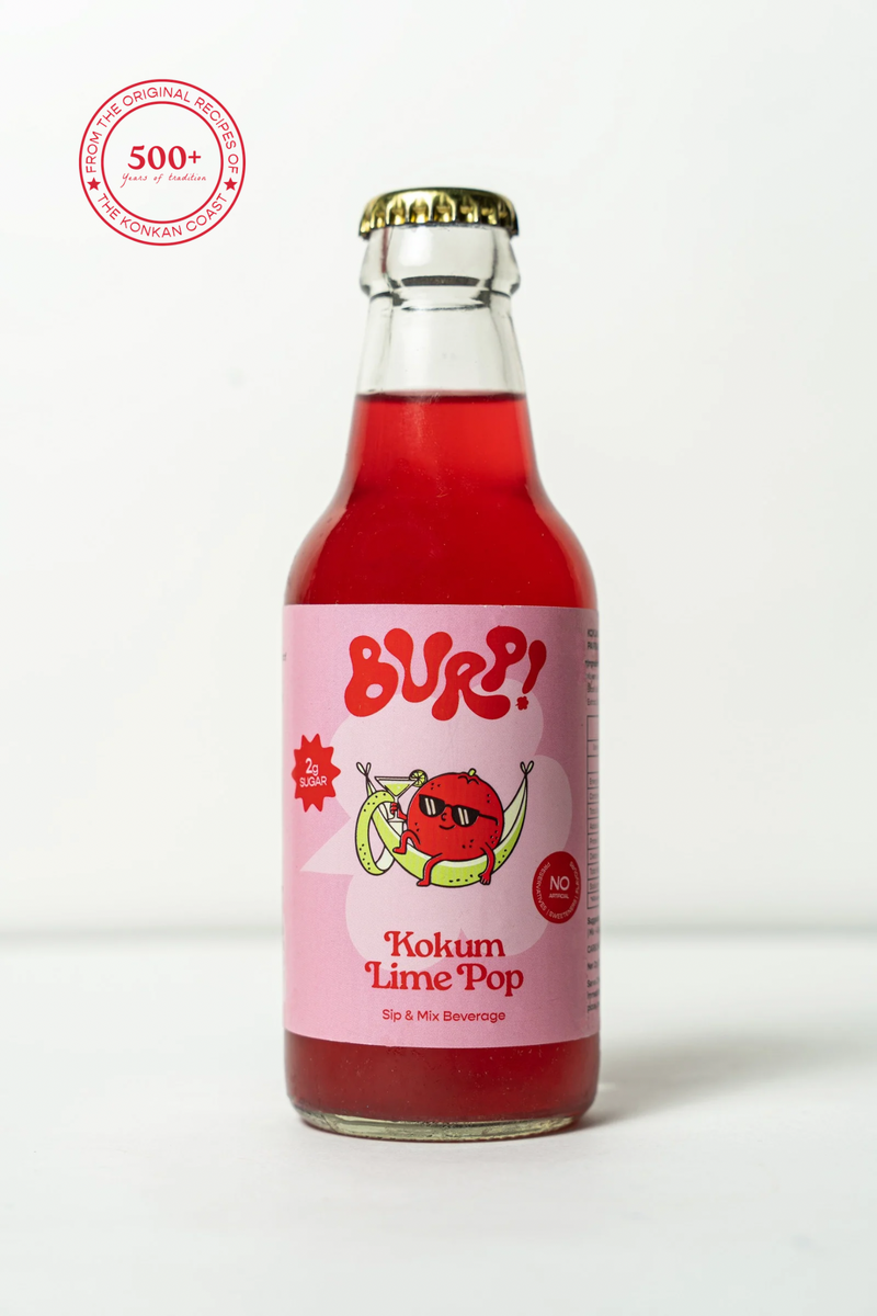 A bottle of BURP! Kokum Lime Pop sparkling beverage, featuring a pink label with a cartoon lime character and a gold crown cap, set against a plain white background with a 500+ brand badge in the top left corner.