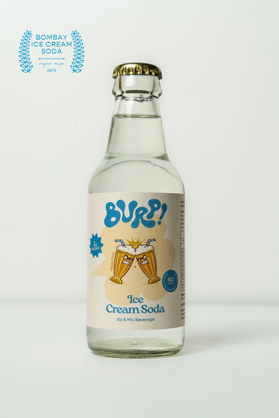 A clear glass bottle of Burp! Ice Cream Soda with a gold cap and a cream-colored label featuring blue and yellow graphics, set against a plain white background with a laurel award badge in the top left corner.